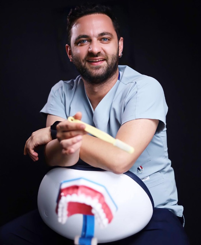 Dt. Ahmet Uğur Balkaş — Taksim diş hekimi, diş modeliyle stüdyo portresi
